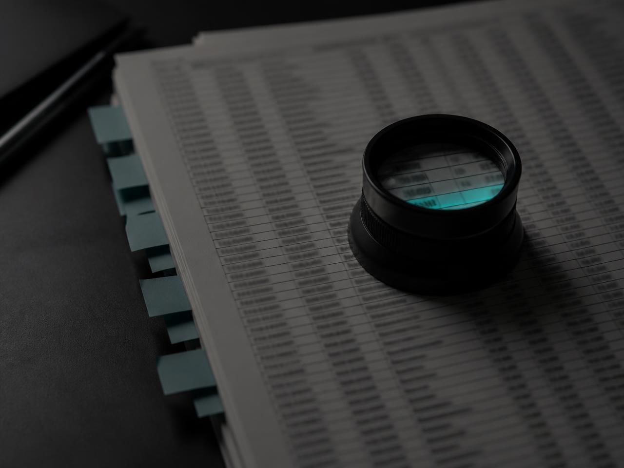 A loupe resting on a printed property schedule with tabbed pages